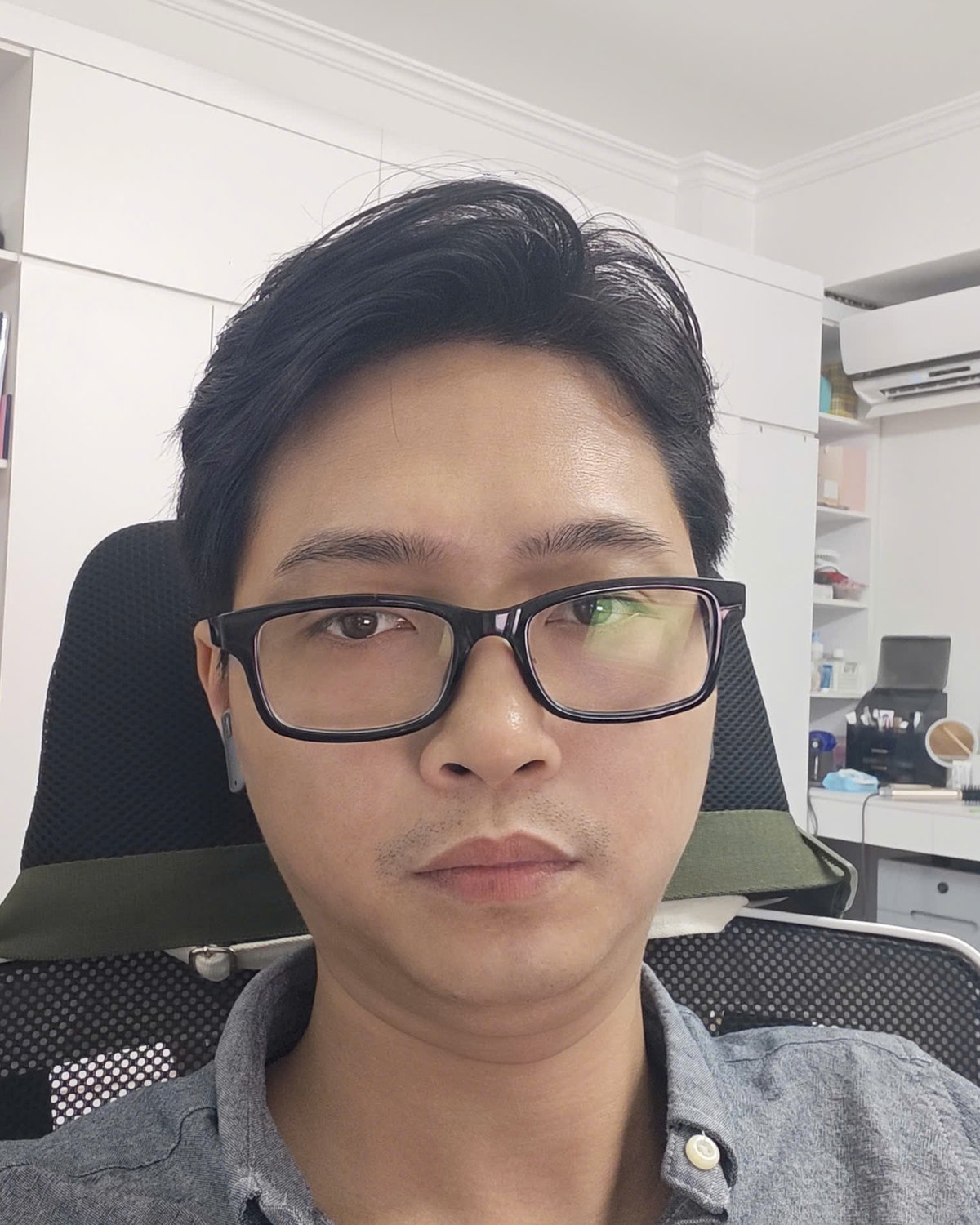 Nguyễn Thanh Tùng, đeo kính, mặc sơ mi xám, ngồi ở bàn làm việc